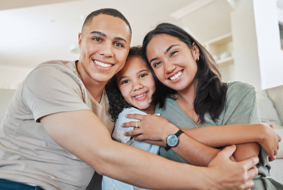 Familia abrazada sonriendo en casa