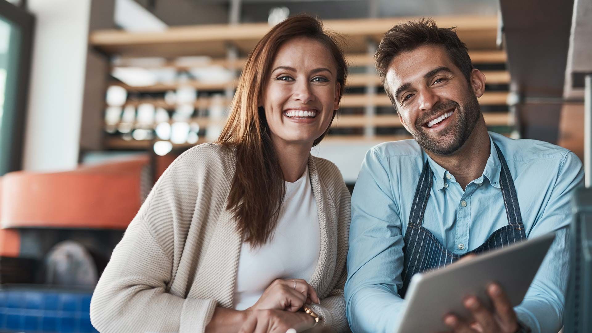 Dueños de restaurante sonriendo con su seguro comercial