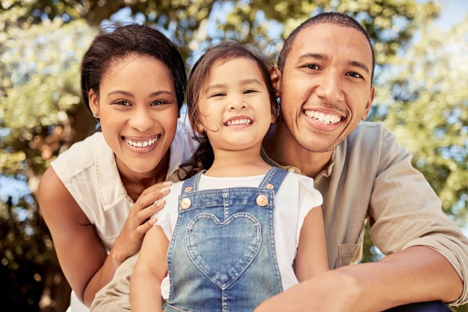 Padres y su hija sonriendo en primer plano al aire libre
