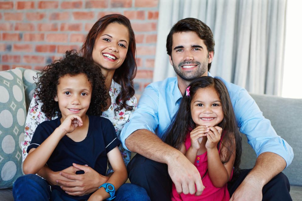 Familia sonriendo junta en la sala de su casa