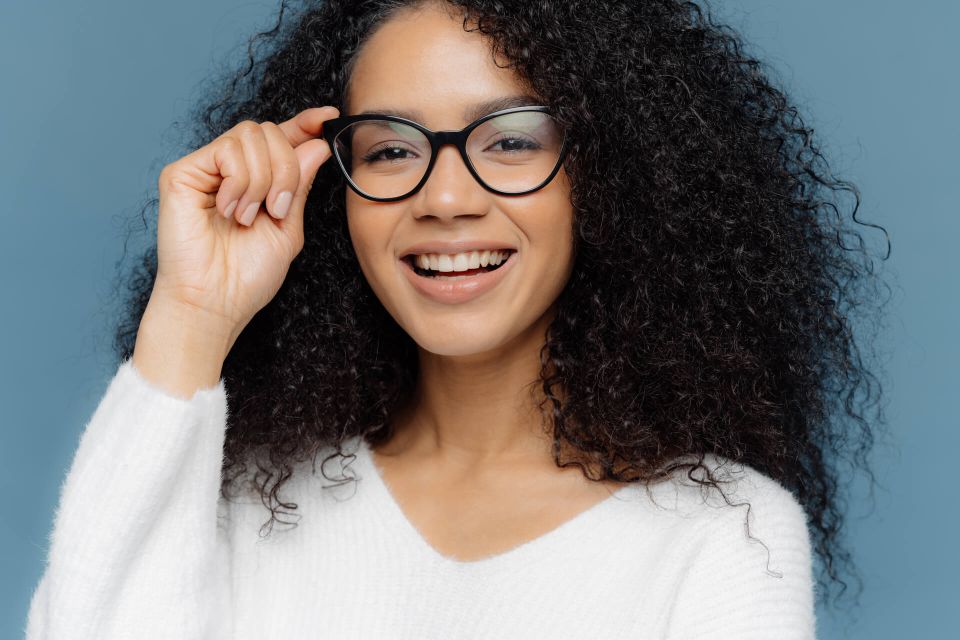 Mujer sonriendo mientras ajusta sus gafas