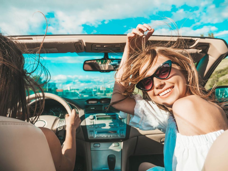 Mujer sonriendo en un auto descapotable durante un viaje