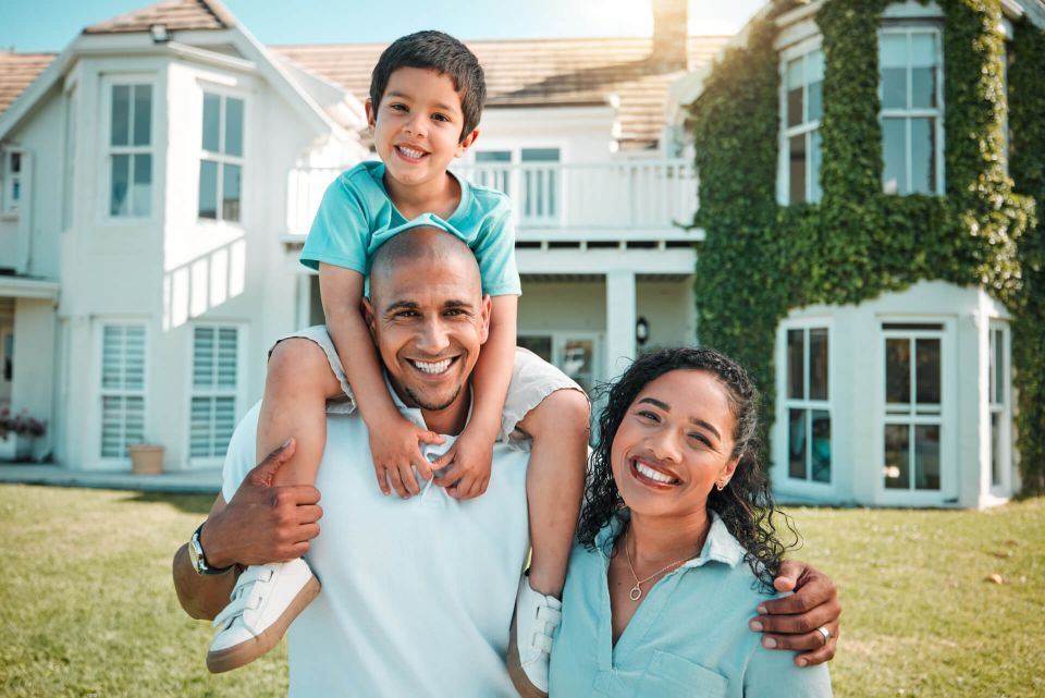 Familia sonriendo frente a su vivienda